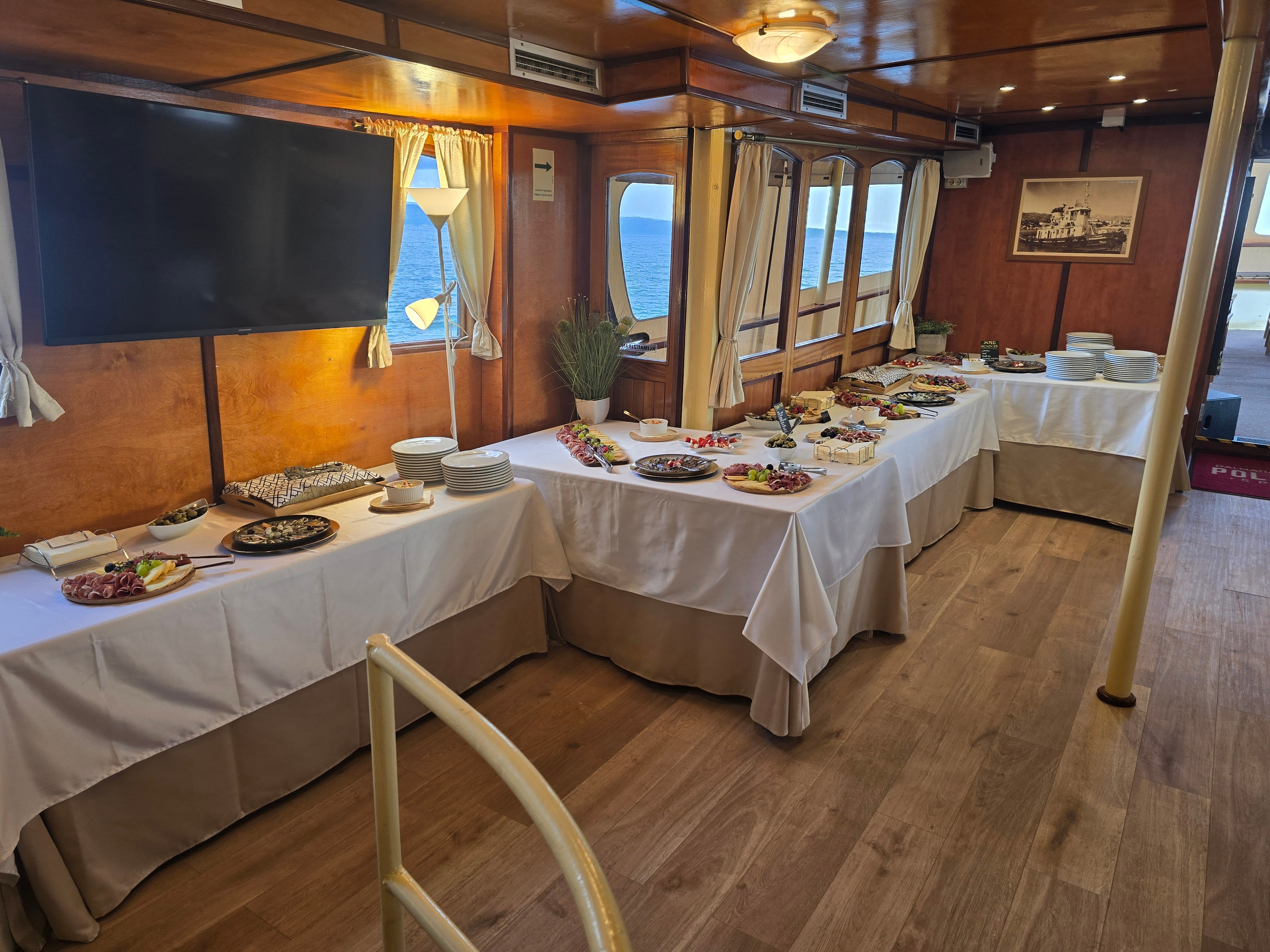 Onboard buffet of Dalmatian charcuterie and cheese boards, salads and canapés set along the salon windows with the open sea beyond