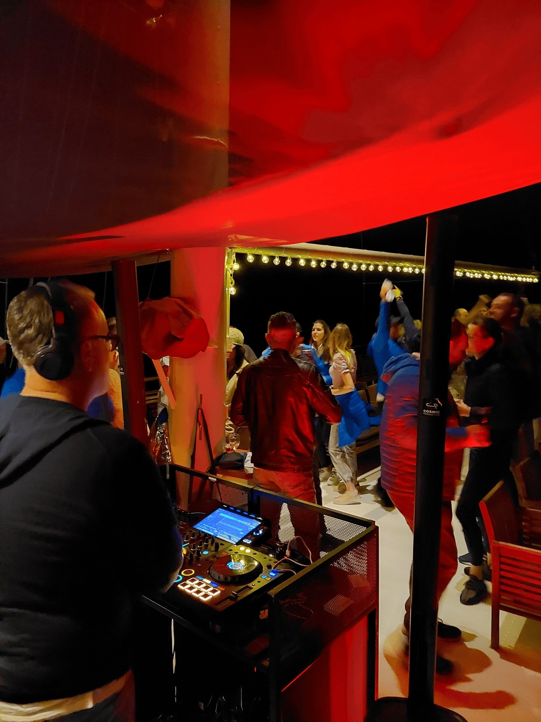DJ legt auf, während Gäste unter warmen Lichterketten bei einem Nachtevent an Deck der Yacht Polaris tanzen