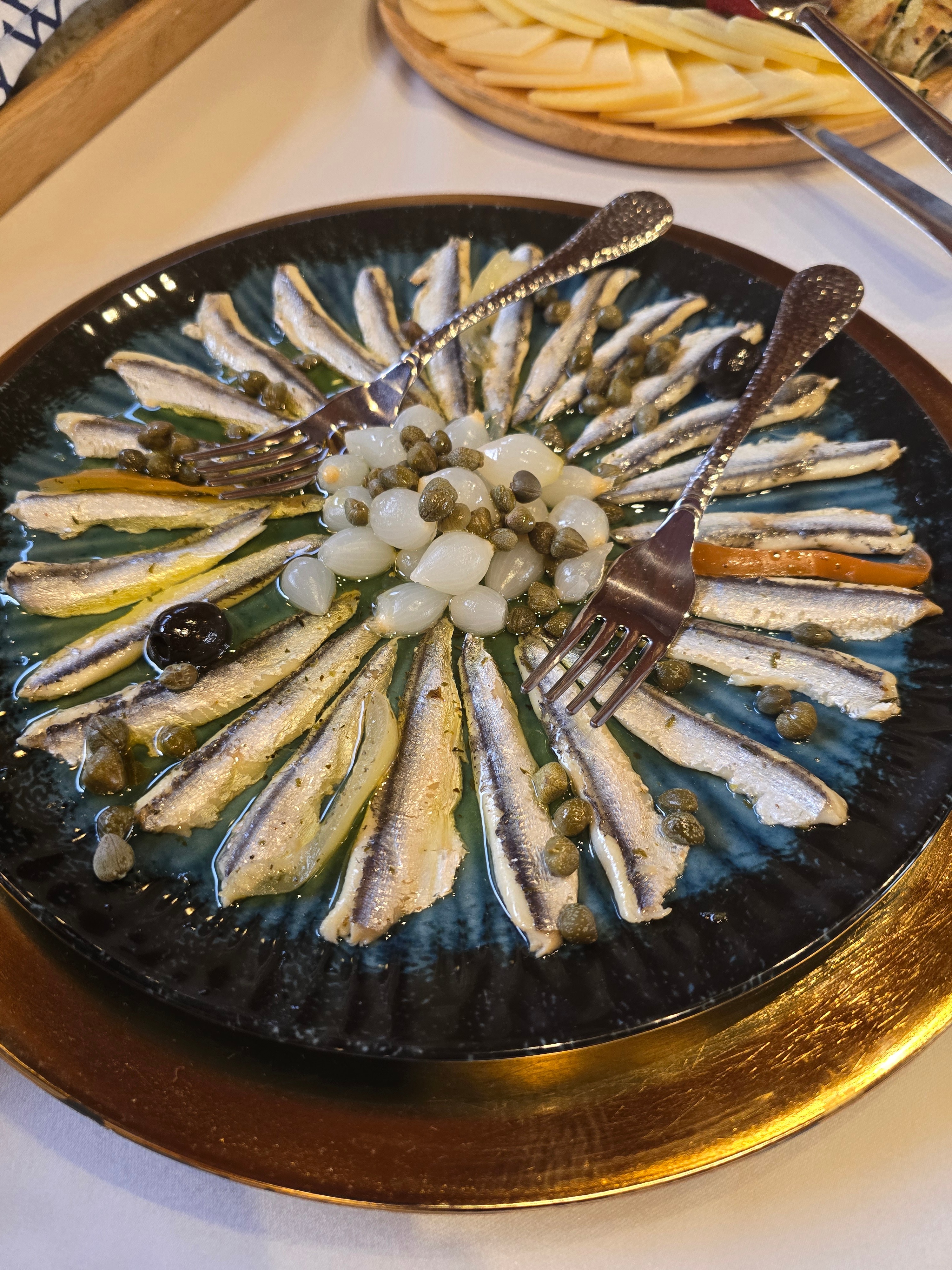 Marinated Adriatic anchovies arranged in a sunburst with pearl onions and capers