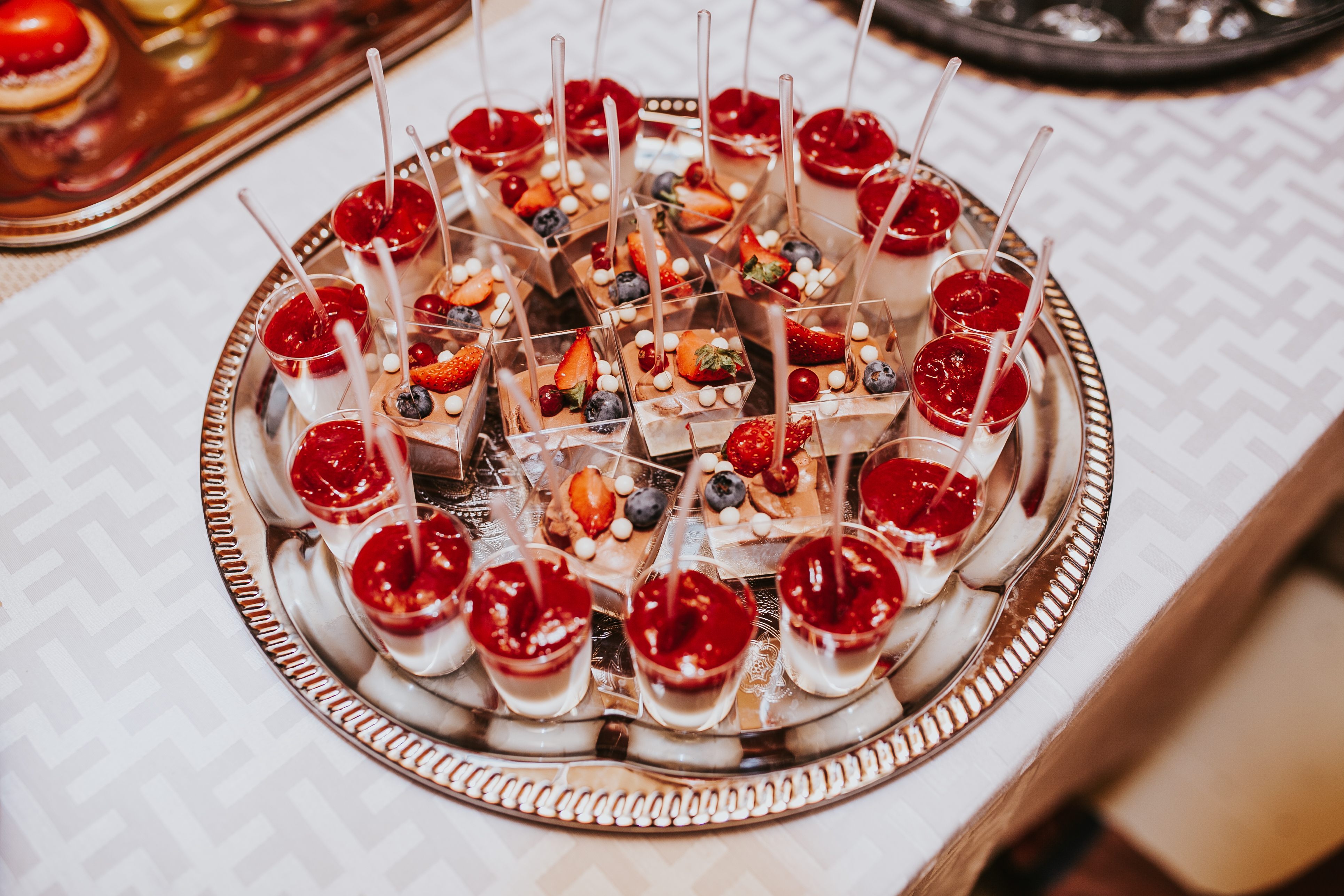 Silbertablett mit Dessertgläschen, frischen Beeren und weißen Schokoladenperlen