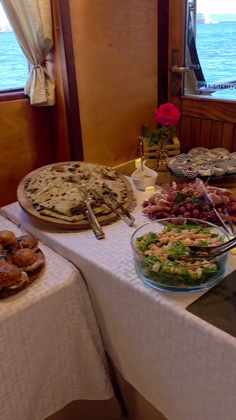 Bordbuffet mit Soparnik, Aufschnitt und frischem Salat an den Salonfenstern mit der Adria im Hintergrund