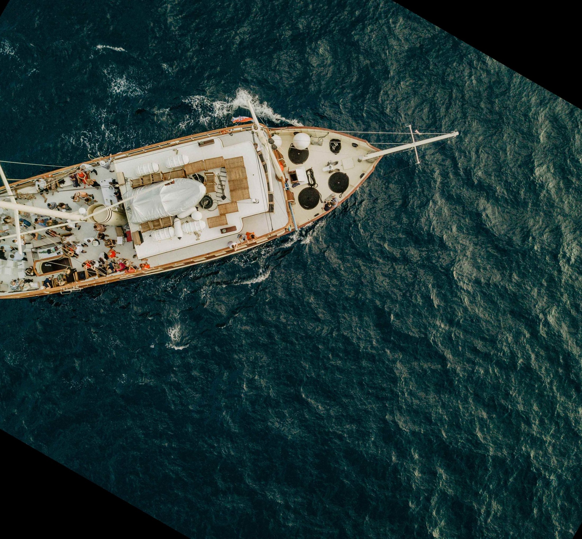 Aerial view of the yacht Polaris cruising through the deep blue Adriatic with guests gathered on the sunlit deck