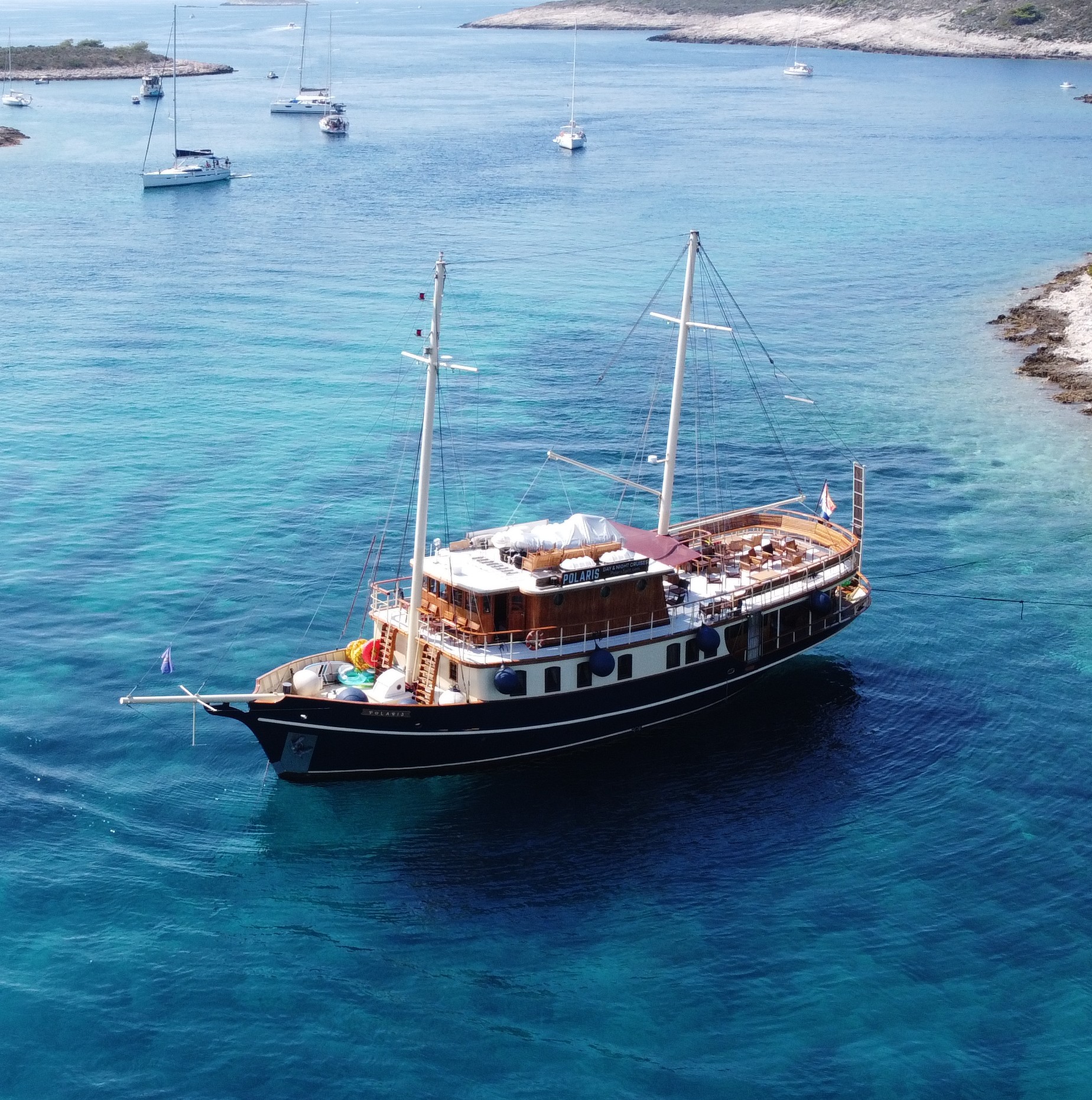 The restored Polaris today, a two-masted wooden cruise ship anchored in the clear turquoise waters of the Adriatic