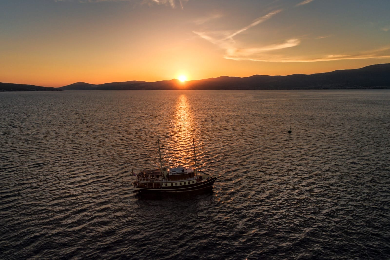 Luftaufnahme der ankernden Polaris, während sich die untergehende Sonne im Wasser spiegelt