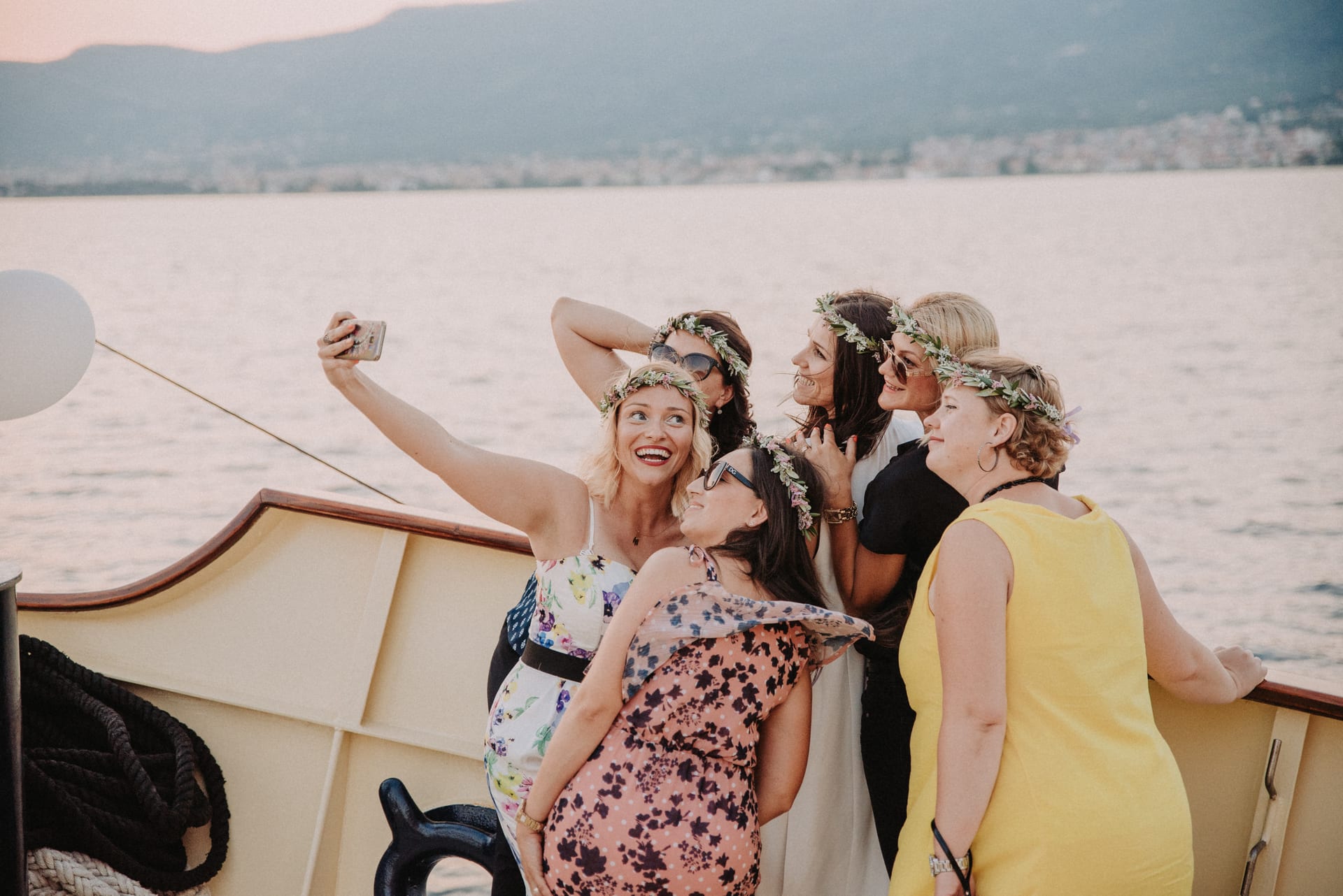 Freundesgruppe mit Blumenkränzen macht ein Selfie bei Sonnenuntergang