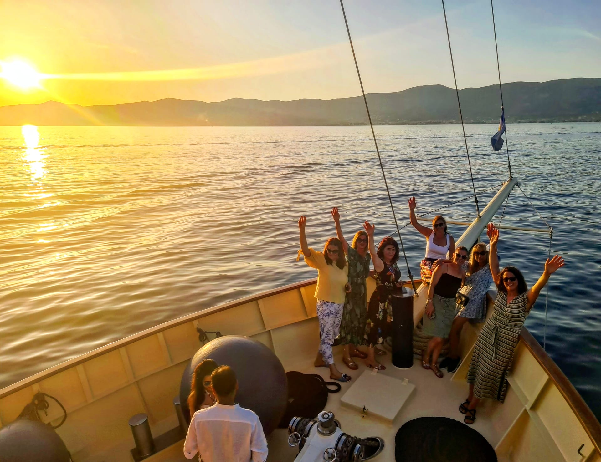 Gruppe von Frauen winkt vom Bug der Polaris im warmen Abendlicht