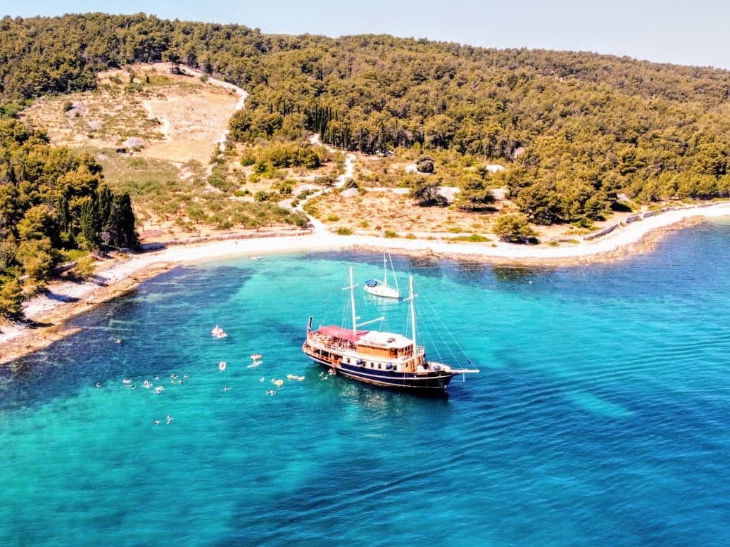 Luftaufnahme der Polaris vor Anker in einer abgelegenen türkisfarbenen Bucht an einem Kiesstrand