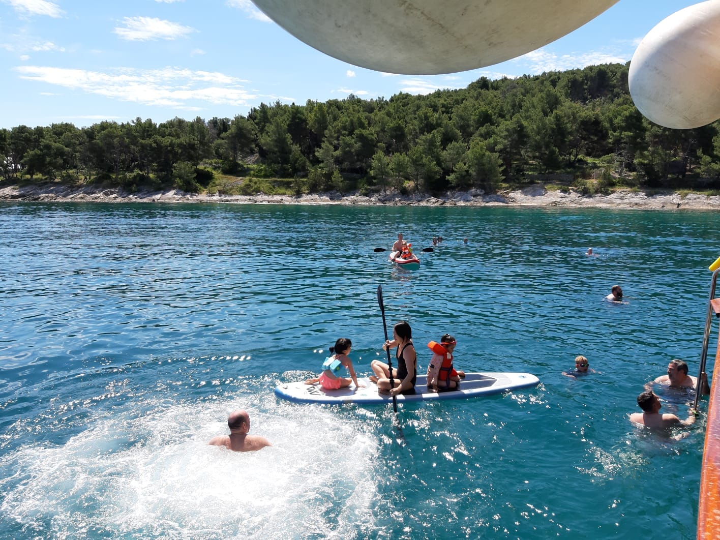 A family paddle boarding near the forested coast