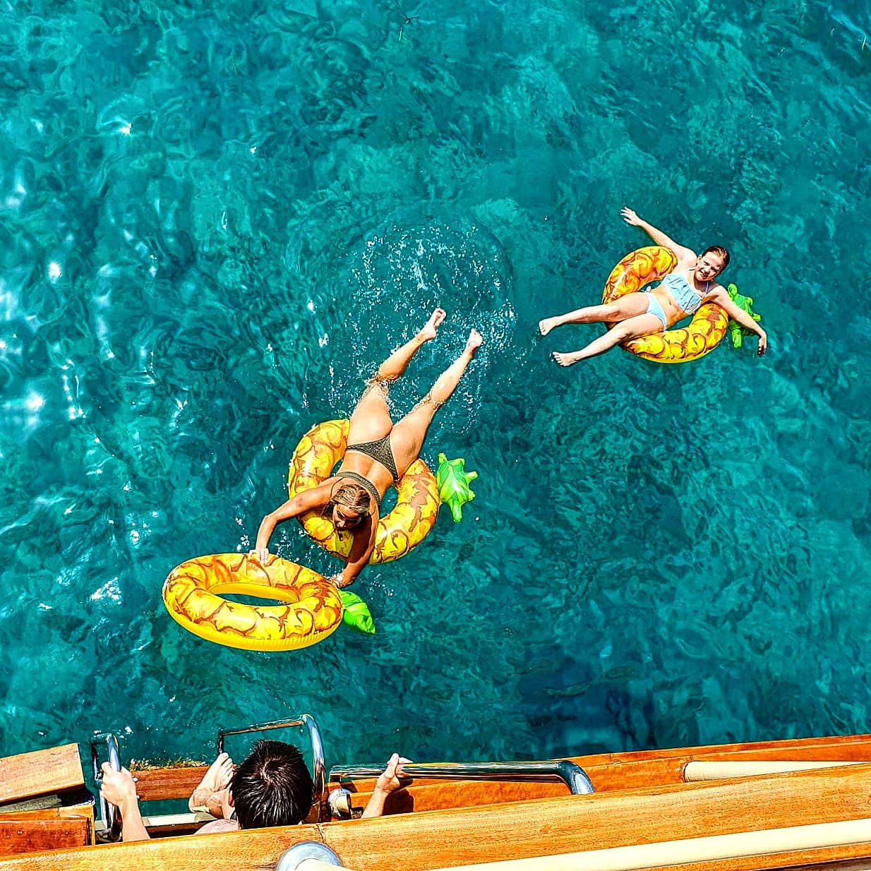 Gäste entspannen auf Ananas-Schwimmtieren im klaren Wasser