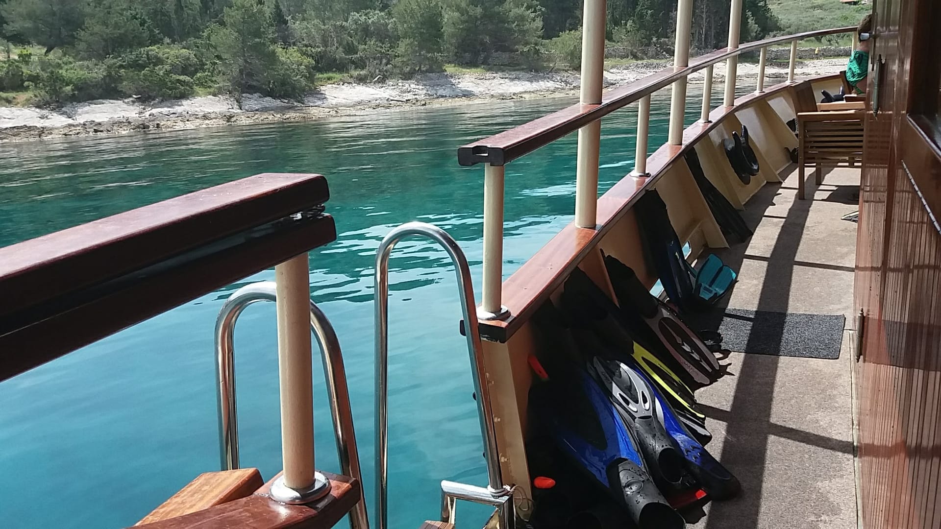 Schnorchelausrüstung und Badeleiter am Deck neben klarem Wasser