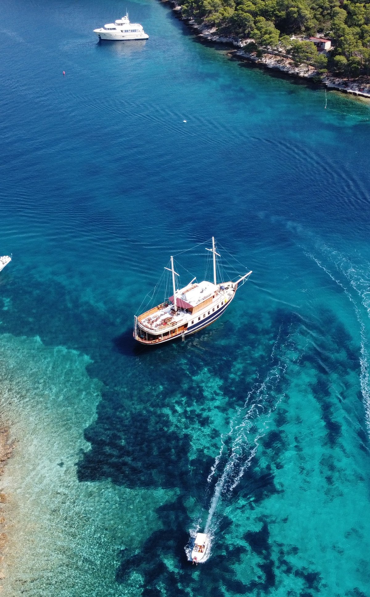 Luftaufnahme der Yacht Polaris vor Anker zwischen Booten in einer türkisfarbenen Adriabucht bei Split