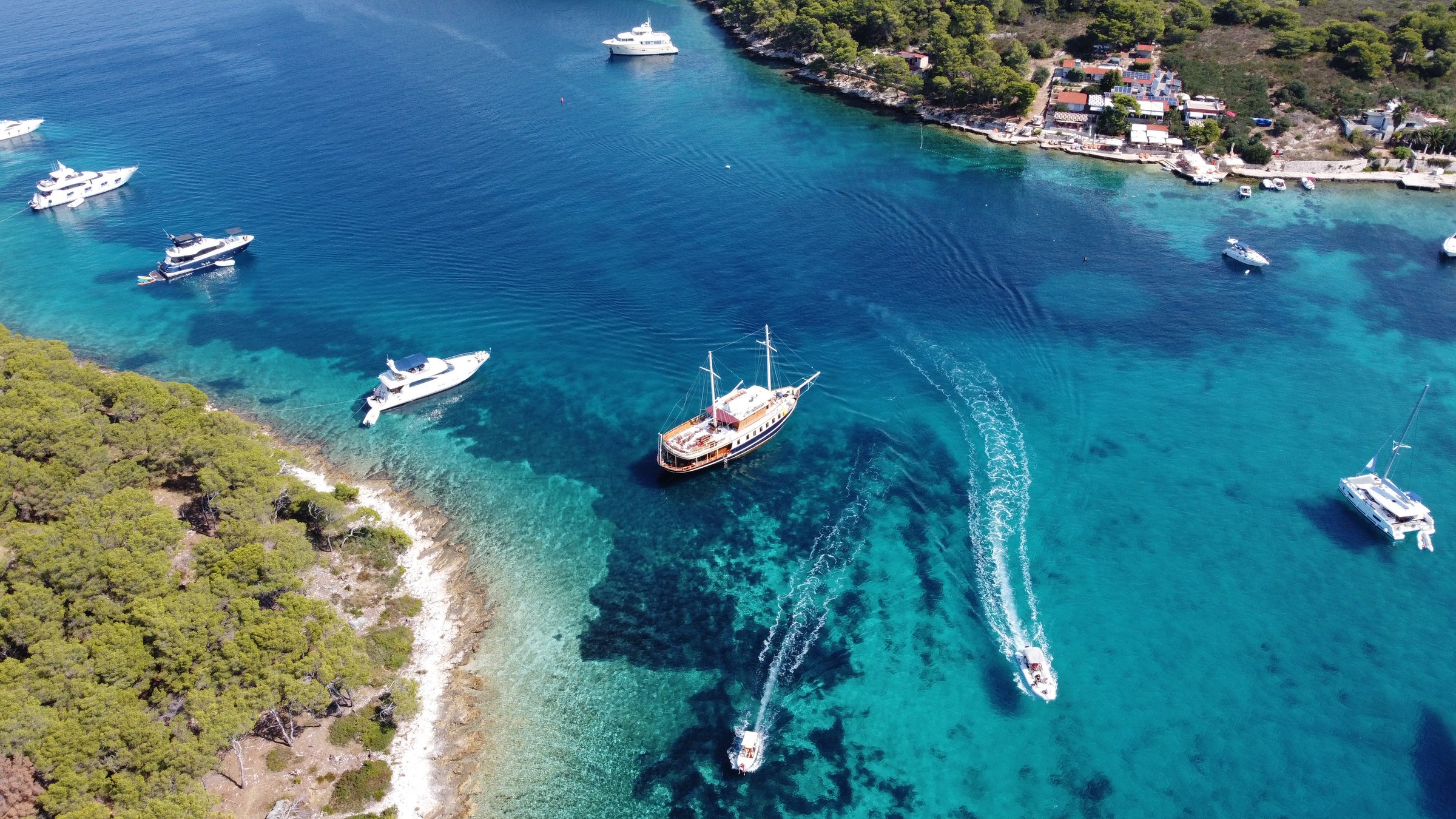Aerial view of the yacht Polaris anchored among boats in a turquoise Adriatic bay near Split